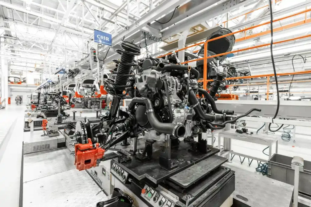 Imagem de uma linha de montagem de motores em uma fábrica moderna, destacando componentes automotivos com alta tecnologia.