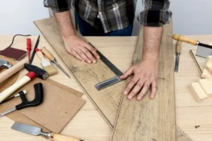 Homem realizando carpintaria com ferramentas e madeira, projetando móveis ou construções em uma oficina de marcenaria.